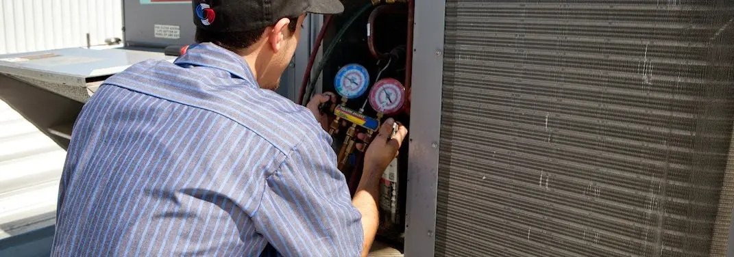 HVAC technician servicing a condenser unit in East Orange
